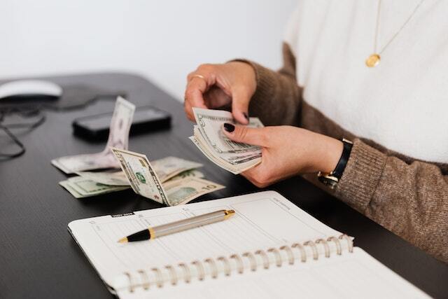 person counting cash and jotting it down in notebook